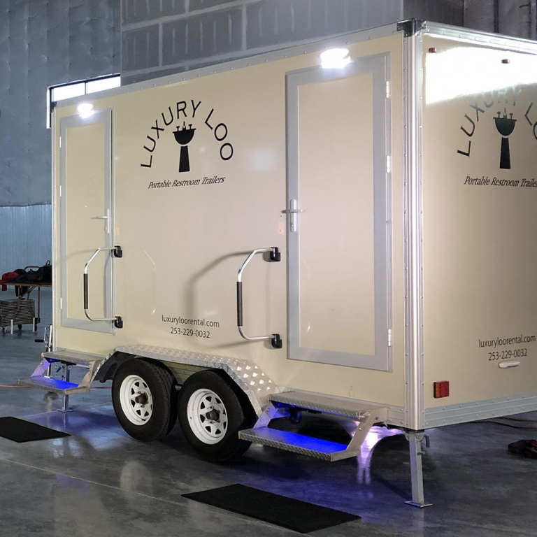Image of Portable Restroom Rentals Two, a white trailer with a lit up step to the door.